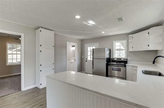 a hall with white cabinets and wooden floor