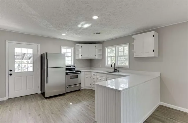 a kitchen with stainless steel appliances a refrigerator sink and white cabinets