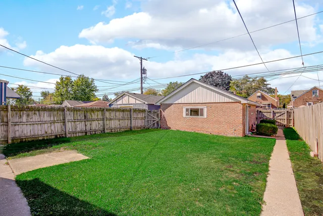 a aerial view of a house next to a big yard and wooden fence