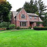 a front view of a house with a garden and trees