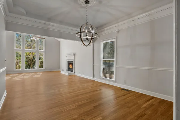 a view of a livingroom with wooden floor a ceiling fan and windows