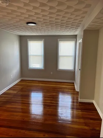 a view of empty room with window and wooden floor