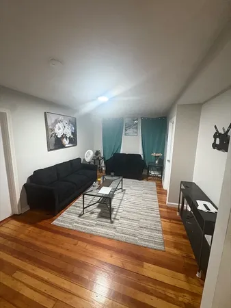 a living room with a bed furniture and a wooden floor