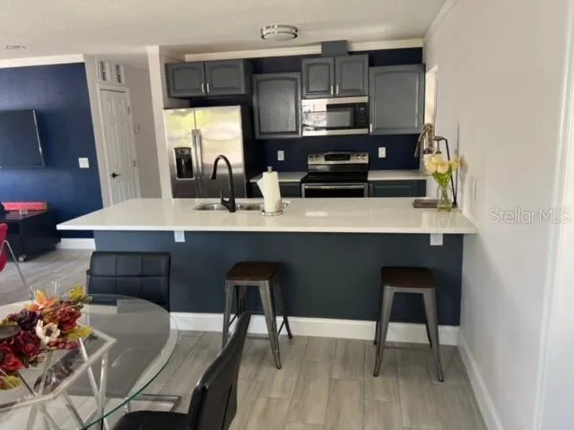 a kitchen with stainless steel appliances a dining table chairs microwave and sink