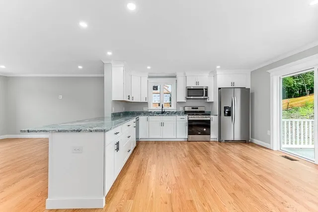 a large kitchen with granite countertop a large counter top stainless steel appliances and cabinets