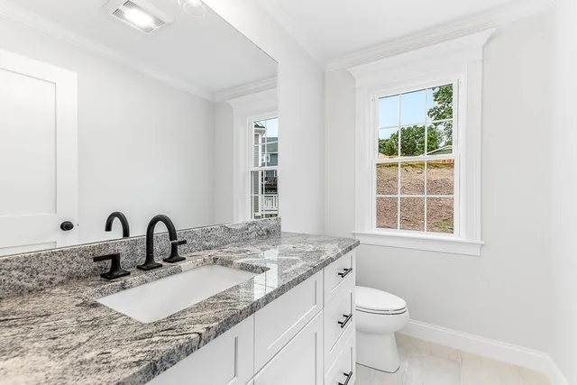 a bathroom with a granite countertop sink a toilet and a window