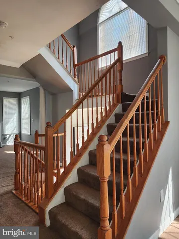 a view of staircase with lots of frames on wall and a baby crib