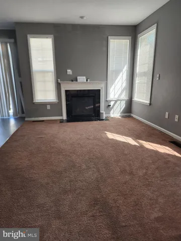 an empty room with windows and fireplace