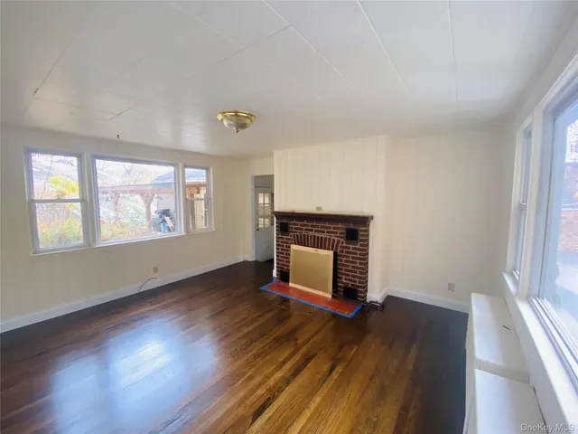 an empty room with windows a fireplace and wooden floor