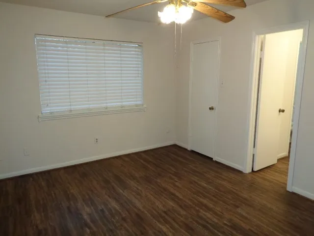 an empty room with wooden floor chandelier fan and windows