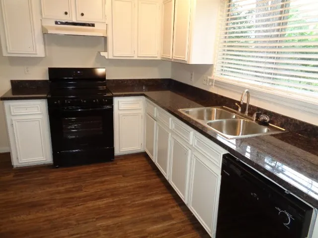 a kitchen with granite countertop a sink stainless steel appliances and cabinets