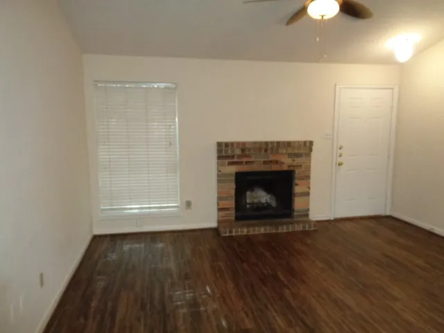 an empty room with wooden floor a fireplace and a chandelier fan