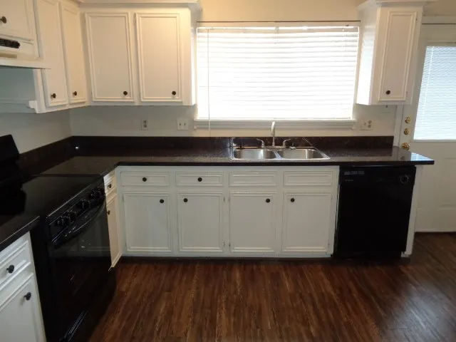 a kitchen with granite countertop white cabinets and sink