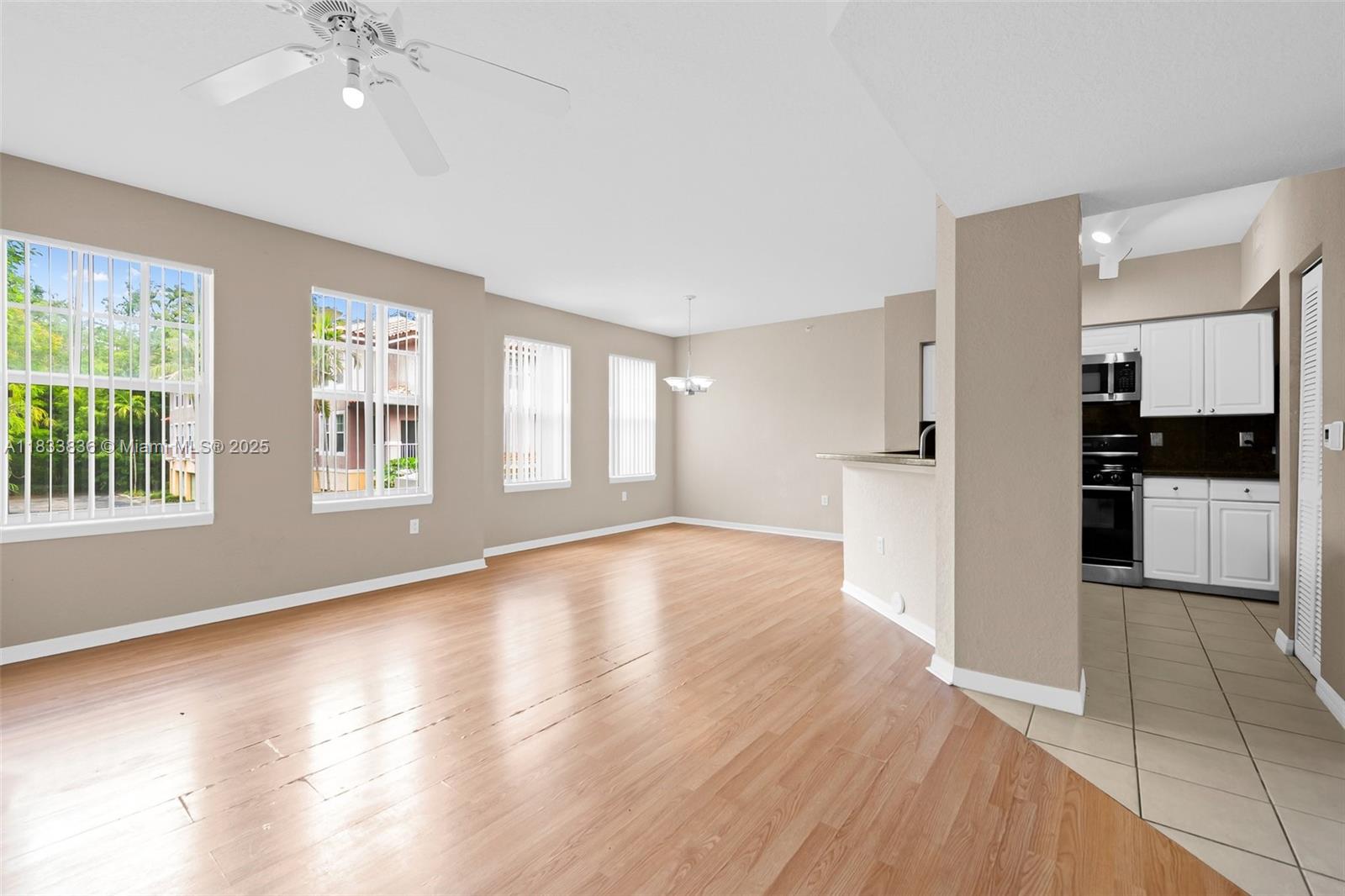 6722 West Sample Road, Unit 6722 Coral Springs, FL 33067 - Photo 3 of 23 a view of an empty room with a kitchen stove and wooden floor
