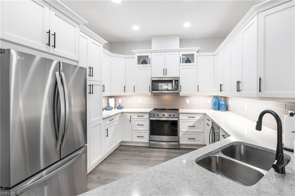 6847 Saona Court Naples, FL 34113 - Photo 2 of 47 a kitchen with stainless steel appliances white cabinets a sink a stove a refrigerator and white cabinets