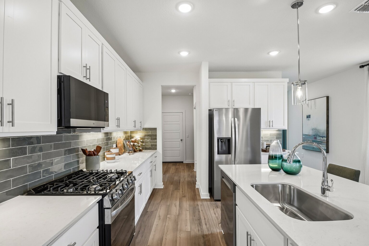 10609 Trifecta Way Buda, TX 78610 - Photo 16 of 17 A well-appointed kitchen features stainless steel appliances, pristine white cabinetry, and durable wood flooring.