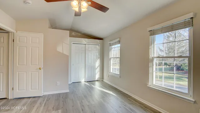 a view of an empty room with a window and wooden floor