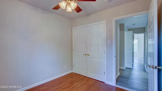 an empty room with wooden floor closet and windows