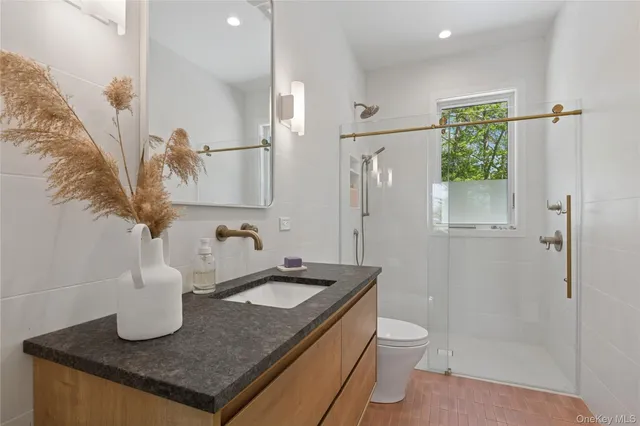 a bathroom with a granite countertop sink a toilet and shower