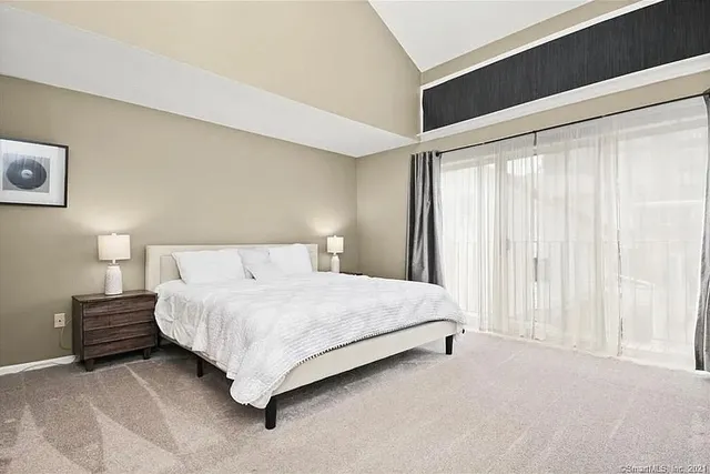 a bedroom with a bed lamp and a large window