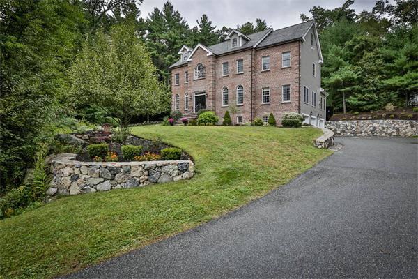 a view of a brick house with a yard and large trees