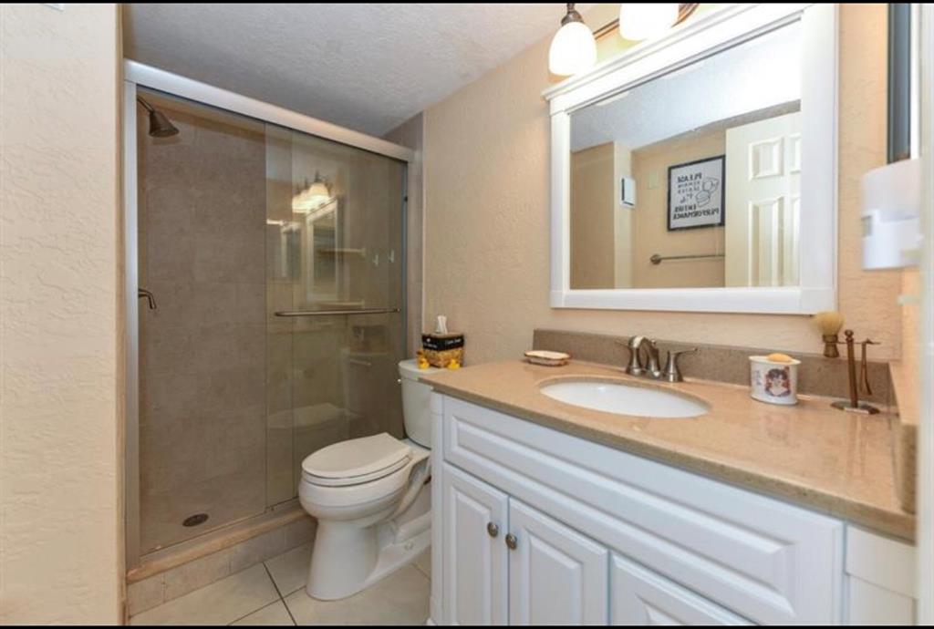 2615 Northeast 3rd Street, Unit 217 Boynton Beach, FL 33435 - Photo 15 of 55 a bathroom with a granite countertop sink a toilet and a mirror