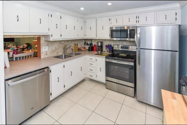 a view of a kitchen with white cabinets and a window
