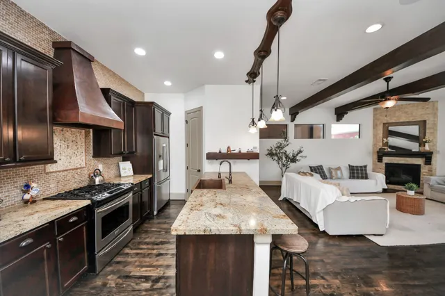 a kitchen with stainless steel appliances kitchen island granite countertop a stove a sink and a refrigerator