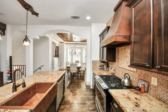 a kitchen with stainless steel appliances kitchen island granite countertop a dining table chairs and a refrigerator