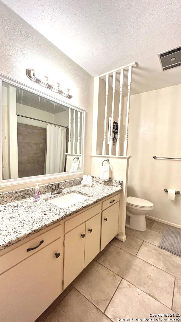 6216 Rue Marielyne Street Leon Valley, TX 78238 - Photo 28 of 35 a bathroom with a granite countertop sink mirror vanity and toilet