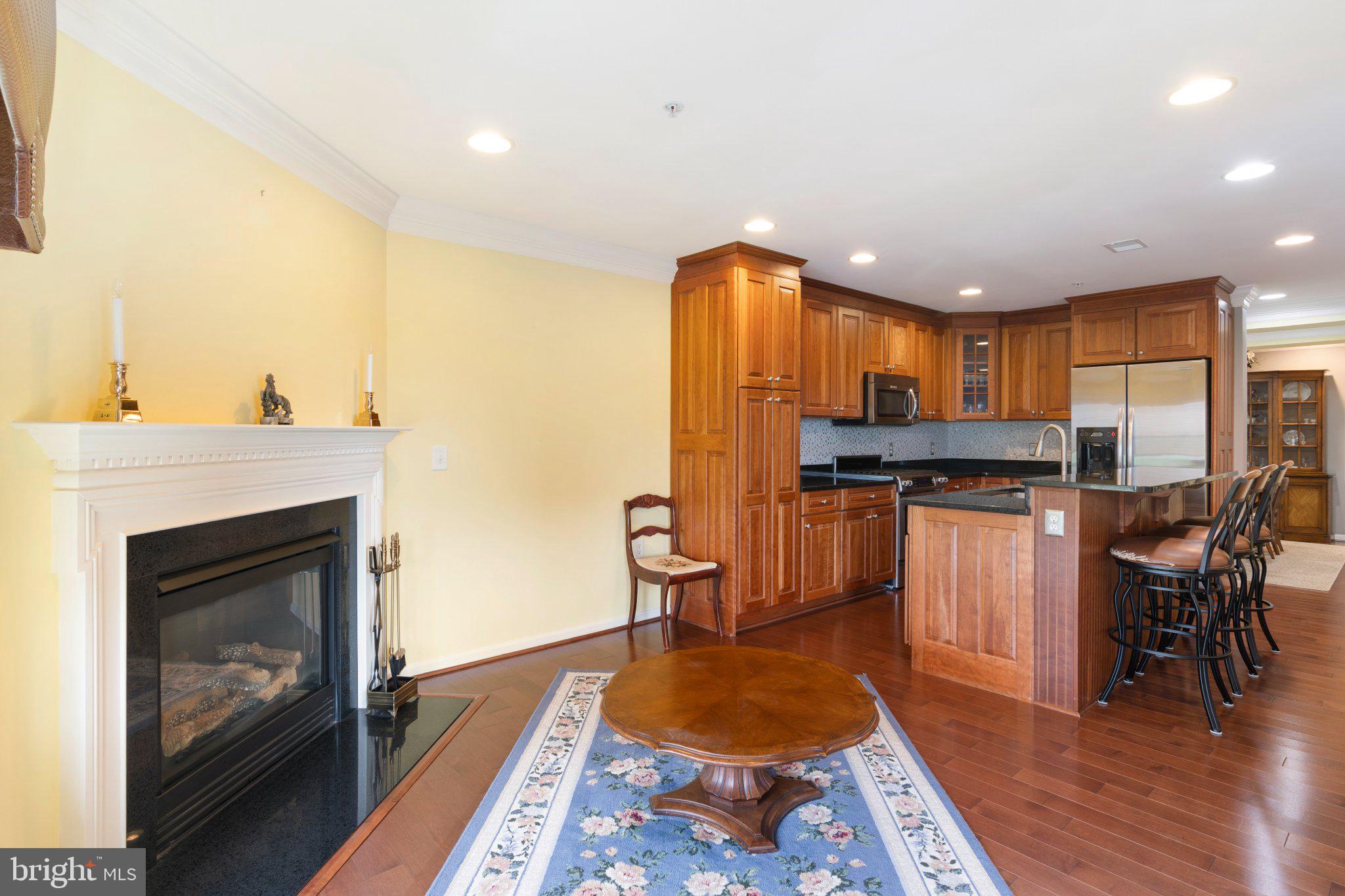 12236 Roundwood Road, Unit 609 Lutherville-Timonium, MD 21093 - Photo 12 of 40 a kitchen with a refrigerator a stove top oven a sink dishwasher and dining table with wooden floor
