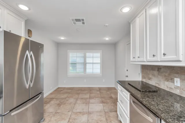 a kitchen with stainless steel appliances granite countertop a refrigerator a sink and white cabinets