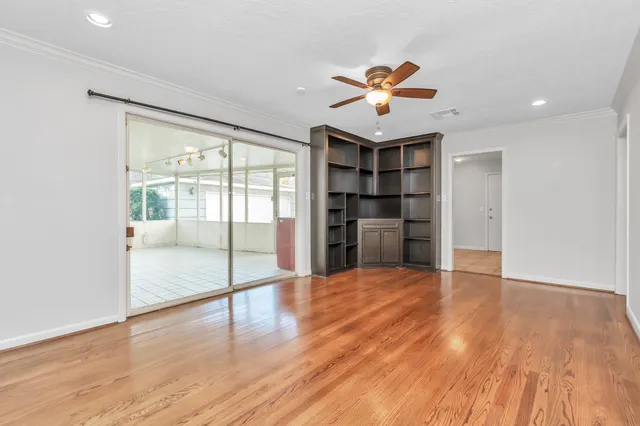 a view of an empty room with a window and wooden floor