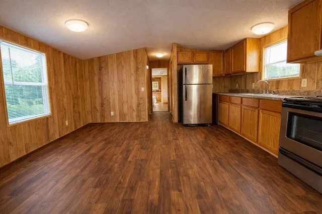 a kitchen with stainless steel appliances granite countertop a refrigerator a stove top oven a sink dishwasher and wooden floor