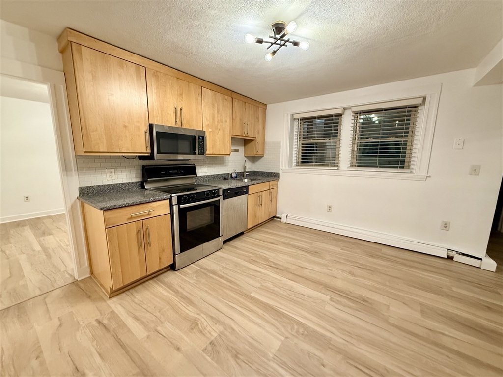 28 Ransom Road, Unit 12AB Boston, MA 02135 - Photo 2 of 17 a kitchen with stainless steel appliances granite countertop a stove top oven a sink dishwasher a microwave oven and a refrigerator with wooden floor