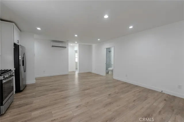 an empty room with wooden floor and a refrigerator