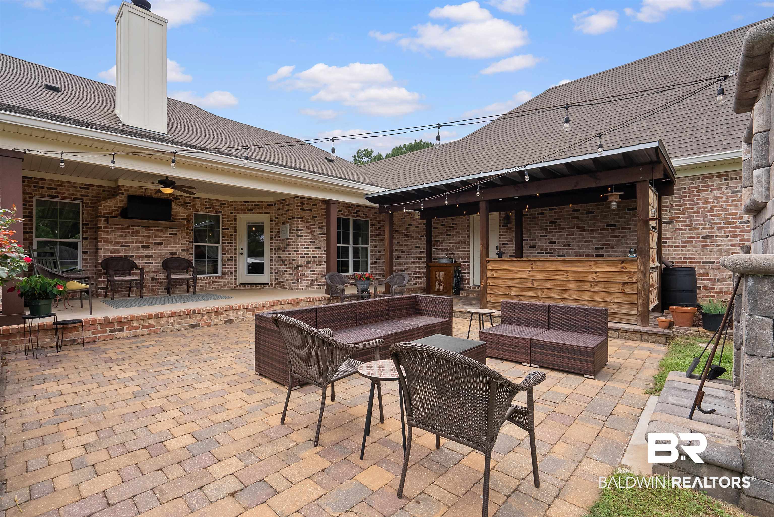 12070 Comalander Road Fairhope, AL 36532 - Photo 42 of 50 Expansive paver patio with a covered porch featuring brick columns and a ceiling fan