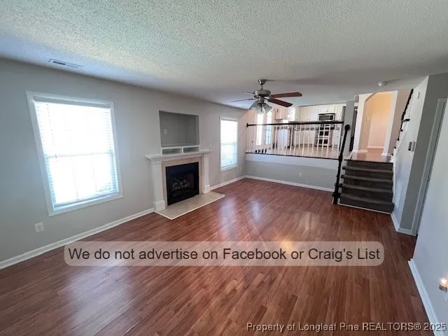 an empty room with wooden floor fireplace and windows