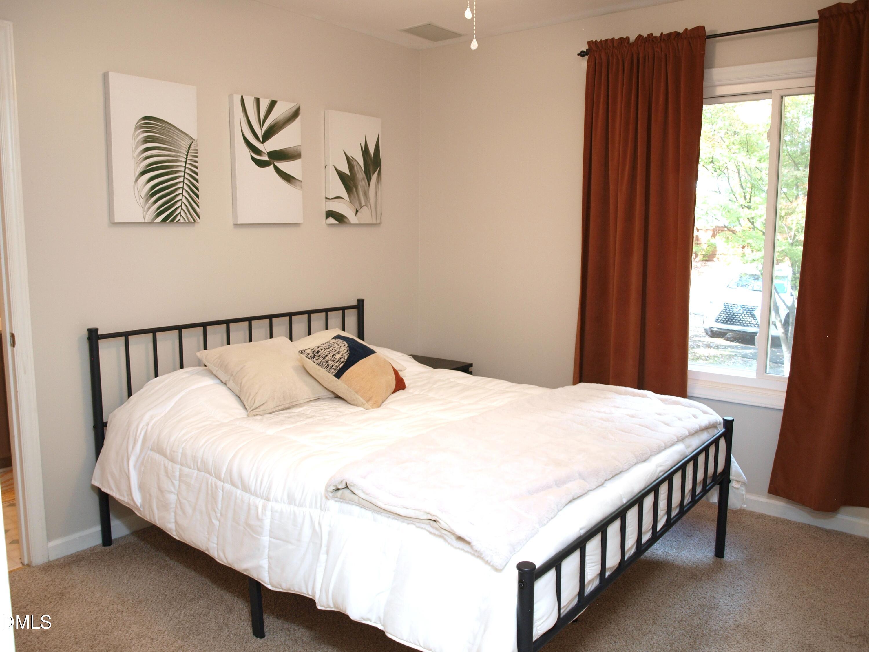 4307 Southwind Drive Raleigh, NC 27613 - Photo 12 of 15 a bedroom with a bed and paintings on the wall