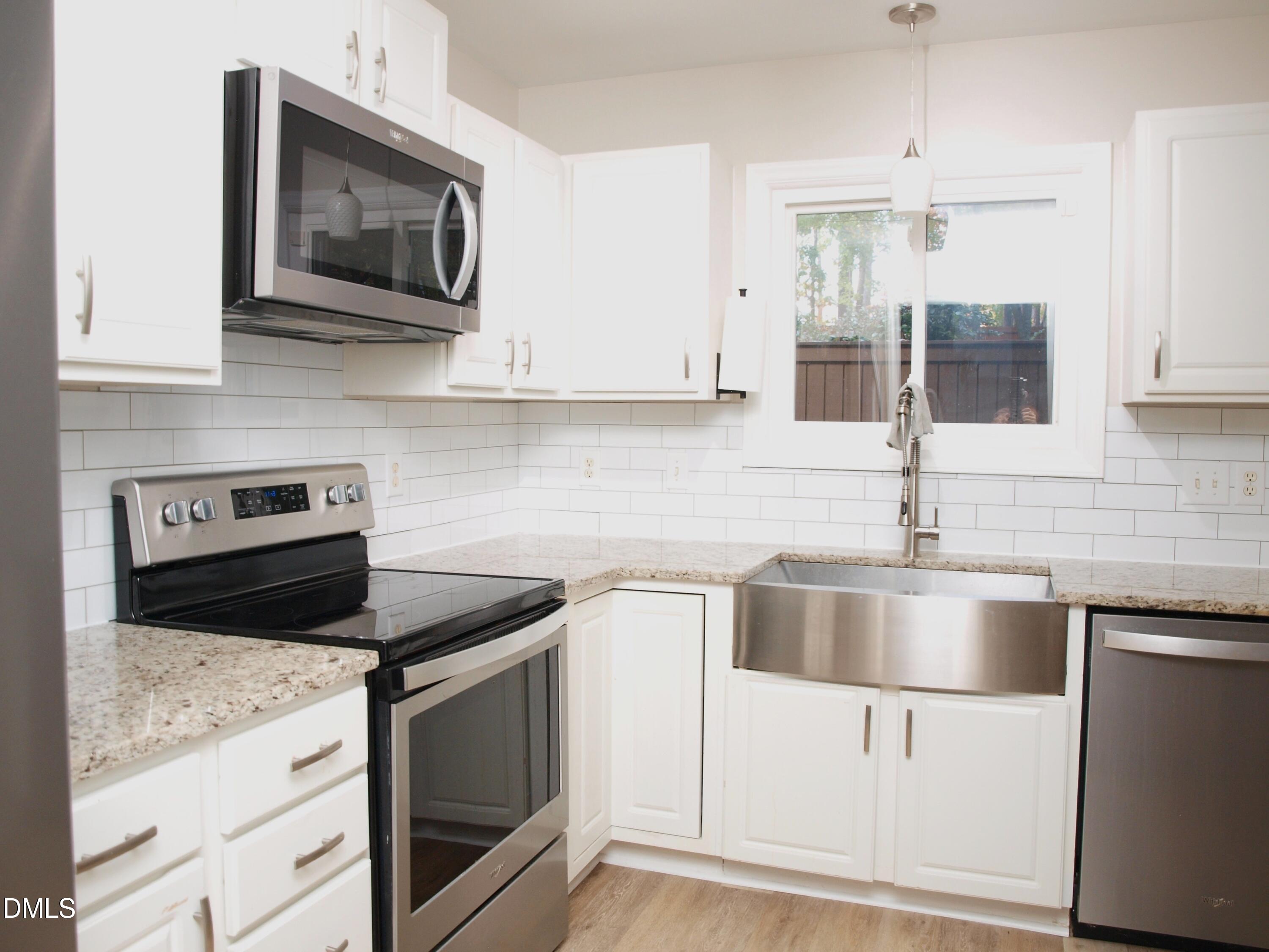4307 Southwind Drive Raleigh, NC 27613 - Photo 7 of 15 a kitchen with granite countertop white cabinets sink and stainless steel appliances