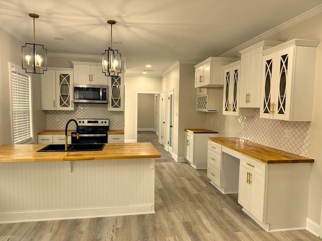 a large kitchen with stainless steel appliances a stove a sink dishwasher a refrigerator white cabinets and wooden floor