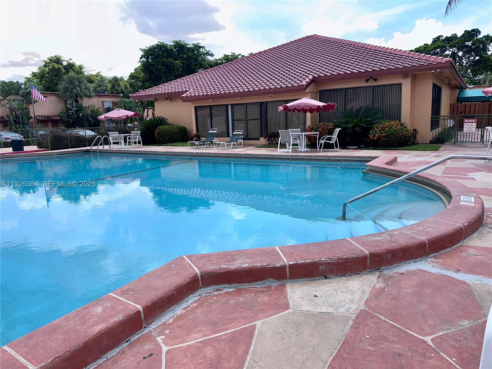 7208 Fairway Drive, Unit I20 Miami Lakes, FL 33014 - Photo 20 of 22 a view of a house with pool lawn chairs under an umbrella