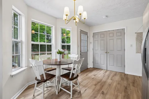 a dining room with wooden floor a chandelier a glass table and chairs