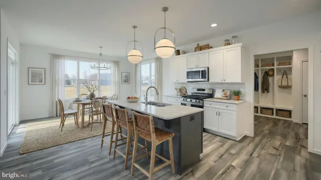 a kitchen with stainless steel appliances granite countertop a stove a sink dishwasher a microwave oven with a dining table and chairs