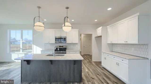 a kitchen with kitchen island granite countertop a stove a sink a center island and cabinets