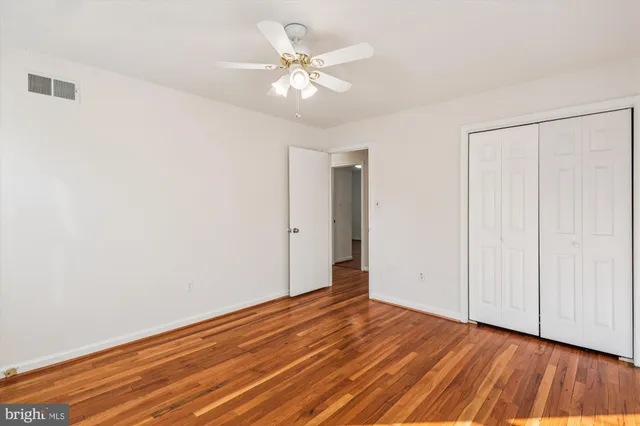 an empty room with wooden floor and fan