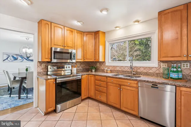 a kitchen with stainless steel appliances granite countertop a stove top oven a sink dishwasher a dining table and chairs with wooden floor