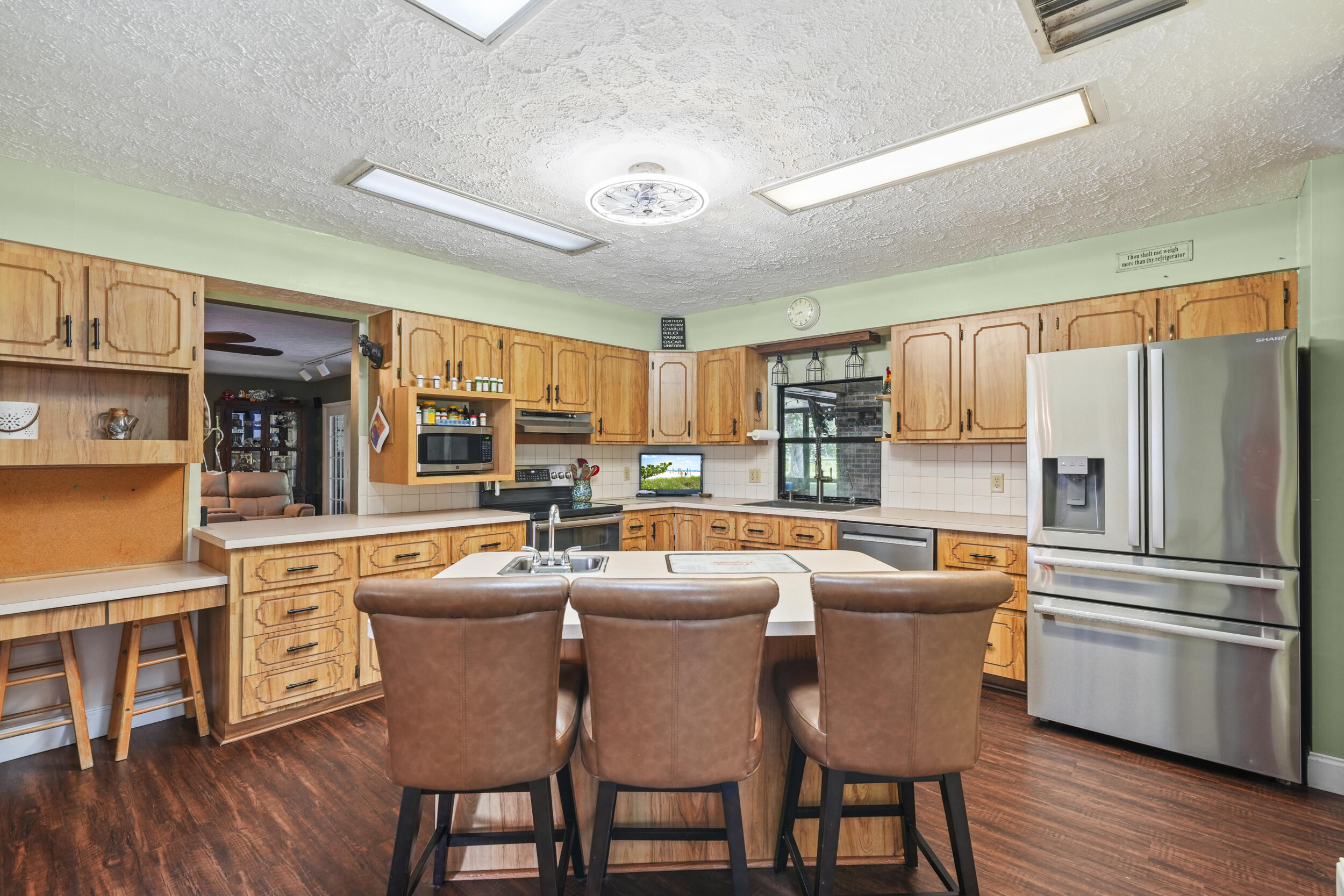 4170 McCarty Road Fort Pierce, FL 34945 - Photo 12 of 57 a kitchen with stainless steel appliances granite countertop a stove a refrigerator a kitchen island a dining table and chairs with wooden floor