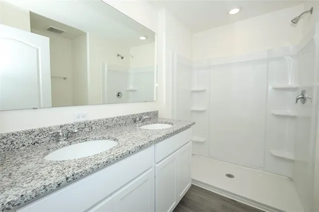 a bathroom with a granite countertop sink a mirror and a shower
