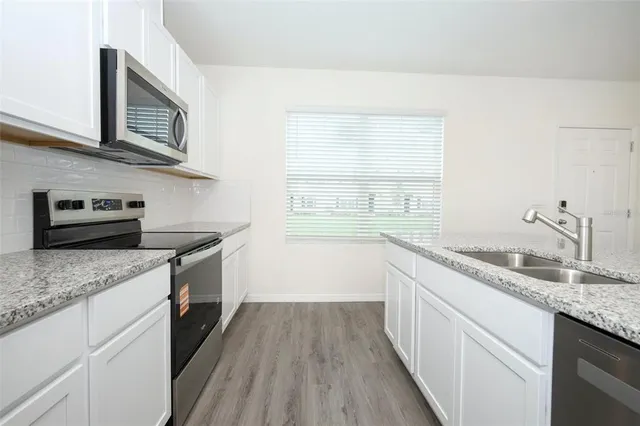 a kitchen with granite countertop stainless steel appliances a stove sink and microwave